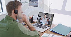 Caucasian man using laptop and phone headset on video call with male colleague