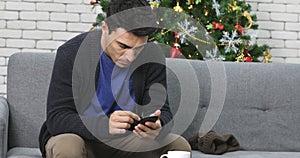 Caucasian man using smartphone on sofa.