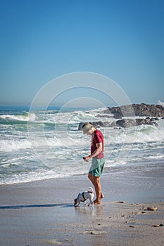 Caucasian Man walking with Jack Russell Terrier dog playing on the beach