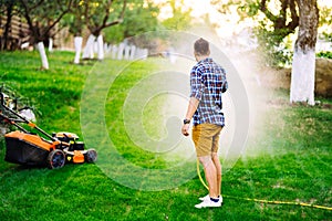Caucasian man watering backyard lawn using hosepipe
