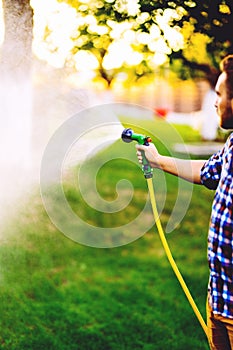 Close up of caucasian man watering backyard lawn using hosepipe photo