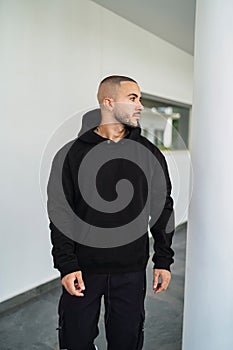 Caucasian man wearing black hoodie standing and looking side