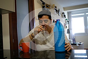 Caucasian man wearing a white T-shirt, drinking a shot of bleach to disinfect himself, following the advice of the US President