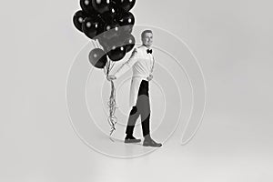 caucasian man in white suit tuxedo with black air balloons