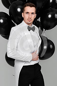 caucasian man in white suit tuxedo with black air balloons