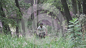 Caucasian man in white T shirt quickly riding black mountain bike along forest path. Male cyclist on mountain bike