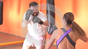 Caucasian man and woman fighting in boxing gloves in the gym, sparring, training