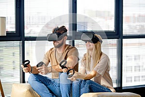 Caucasian man and woman sitting on sofa in living room playing computer video game