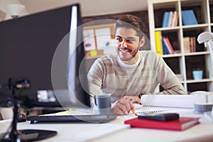 Caucasian man at work desk facing flat screen computer