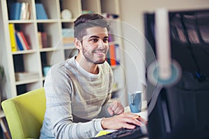 Caucasian man at work desk facing flat screen computer