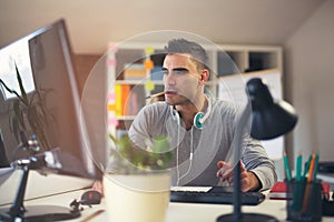 Caucasian man at work desk facing flat screen computer