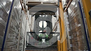 Caucasian man worker loads shelves while sitting in loading machine at industrial warehouse.