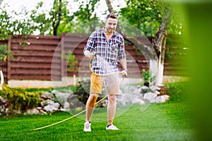 Caucasian man working on grass irrigation. Hose manual system, watering the lawn