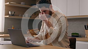 Caucasian man working laptop at kitchen suffer with eyestrain take of glasses. Tired male freelancer businessman work