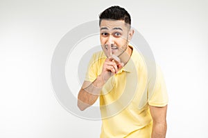 Caucasian man in a yellow T-shirt asks to be quieter on a white isolated background