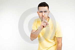 Caucasian man in a yellow T-shirt asks to be quieter on a white isolated background