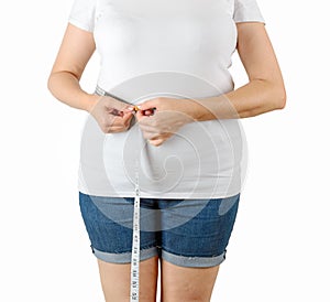 Caucasian mature adult woman begins to gain weight and measures her waist with a measuring tape. Woman dressed in a white T-shirt