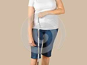 Caucasian mature adult woman dressed in a white T-shirt and a blue denim capris is going to shorten them and measure the desired