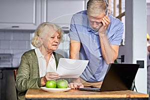 caucasian mature couple checking bills while managing accounts on home banking app