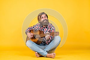 Caucasian mature hipster guitar palyer with trendy hairstyle in checkered shirt love music, singer