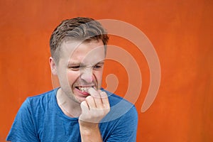 Caucasian mature man on red background gnawing nails.