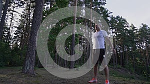Caucasian mature person doing squat exercise with bodyweight in forest.