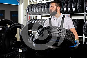 caucasian mechanic holding a tire and showing wheel tires at car repair service and auto store shop