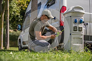 Men Attaching Electric Plug to RV Park Hookup