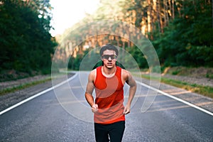 Caucasian middle age man athlete runs sunny summer day on asphalt road in the forest