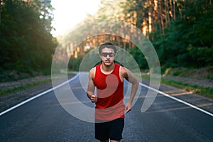 Caucasian middle age man athlete runs sunny summer day on asphalt road in the forest