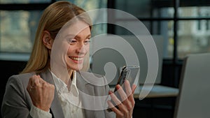 Caucasian middle-aged adult woman mature business lady businesswoman entrepreneur scrolling browsing mobile phone win