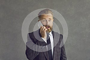 Caucasian middle-aged businessman with a confused expression talking on a mobile phone.