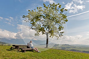 Žena sediaca na letnom kopci pri Liptovskom Trnovci, Slovensko.