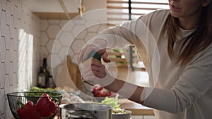 Caucasian middle aged woman tasting a soup and adding some spices.