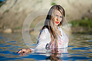 Caucasian model posing in wet white shirt in water.