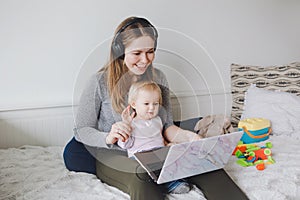 Caucasian mother with baby working online from home on laptop. Freelancer woman with kid calling friends family relatives on