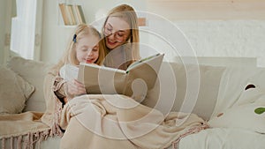 Caucasian mother babysitter woman with little preschool girl child kid reading book fairy tale studying together read