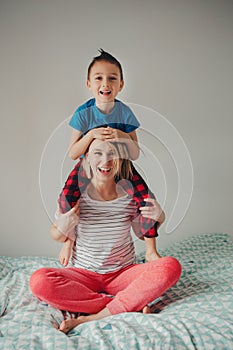 Caucasian mother and boy son playing together in bedroom at home