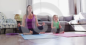 Caucasian mother and daughter having fun meditating in living room