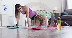 Caucasian mother and daughter practising yoga in living room