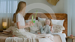 Caucasian mother help cute funny little kid child girl baby blowing soap bubbles playing with happy mom sitting on bed