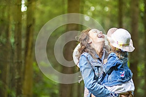 Caucasian Mother with Her Little Daughter Posing Together in Green Summer Forest