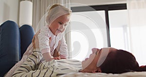 Caucasian mother smiling while playing with her baby on the bed at home