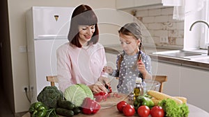 Caucasian mother teach little preschooler daughter chop pepper preparing salad for lunch