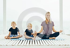 Caucasian mother with two sons practices yoga outdoor