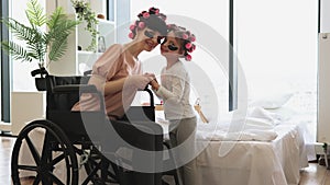 Caucasian mother wheelchair user and little daughter doing cosmetic procedures.
