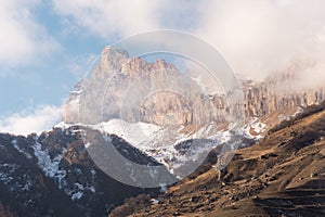 Caucasian mountains. Rock Likoran in Upper Balkaria in the clouds. Winter landscape of bald mountains.