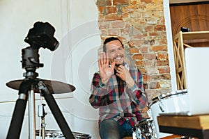 Caucasian musician playing drumms during online concert with the band at home isolated and quarantined, greeting