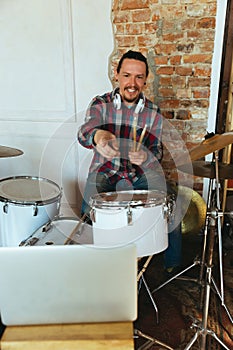 Caucasian musician playing drumms during online concert with the band at home isolated and quarantined, greeting