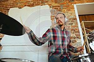 Caucasian musician playing drumms during online concert with the band at home isolated and quarantined, inspired